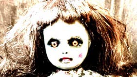 A baby doll dressed in white clothing. It has orange hair and slightly and orange tint.