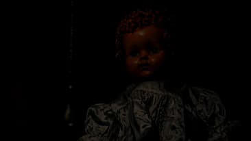 A baby doll dressed in white clothing. It has orange hair and slightly and orange tint.